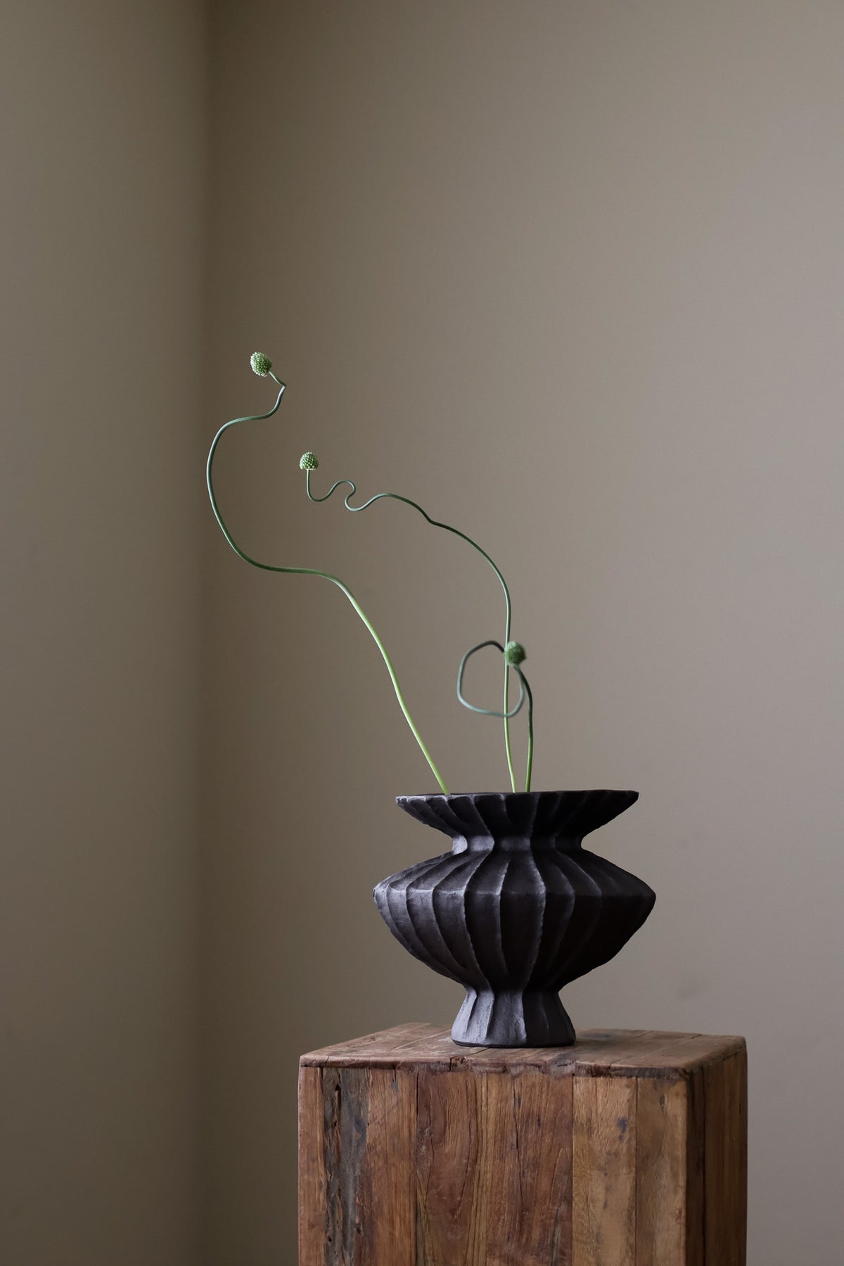 Hand-built dark ceramic vase with a rich, textured ribbed surface and a gently flared rim.