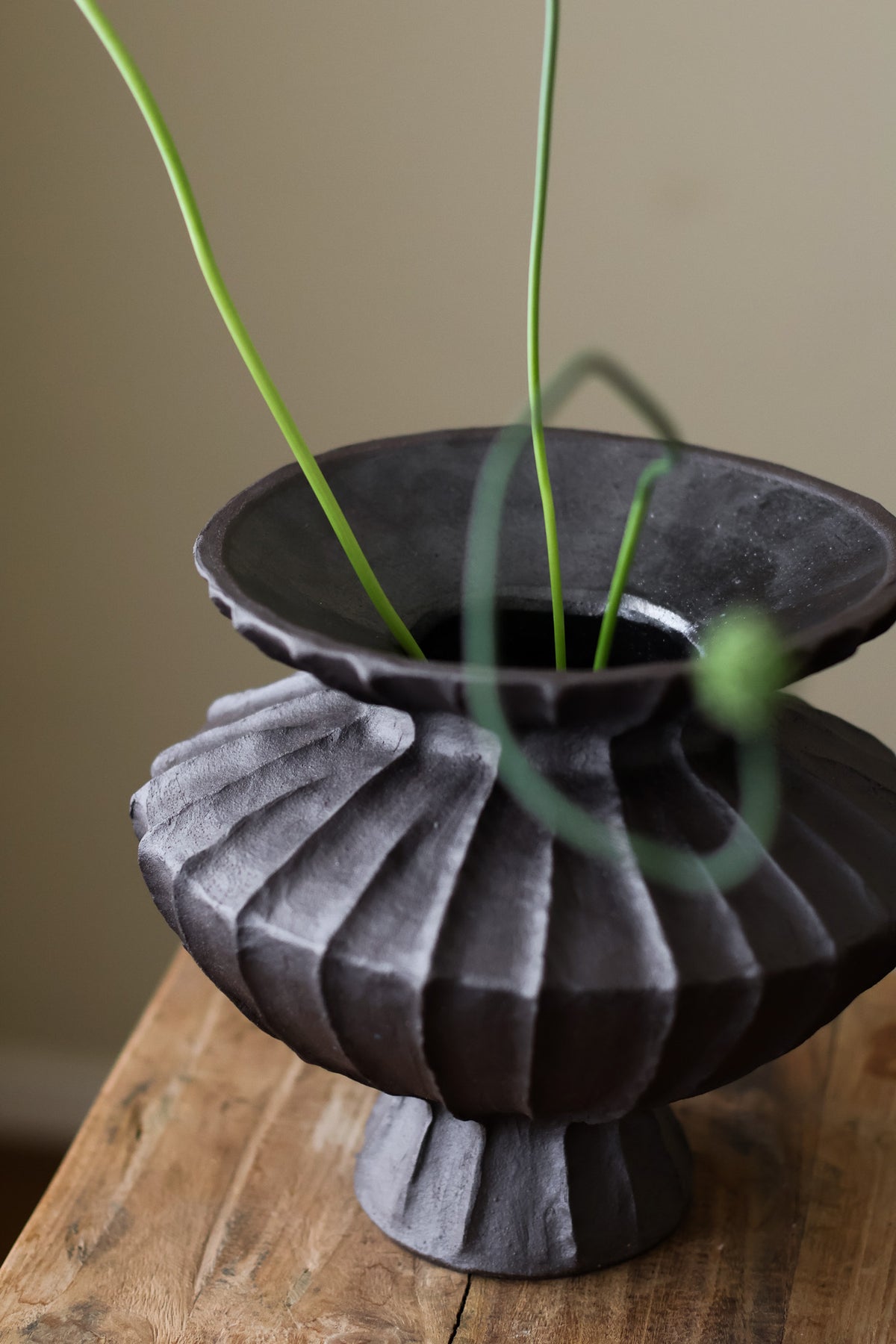 Hand-built dark ceramic vase with a rich, textured ribbed surface and a gently flared rim.