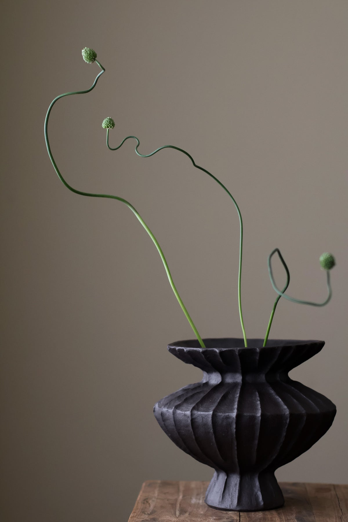 Hand-built dark ceramic vase with a rich, textured ribbed surface and a gently flared rim.