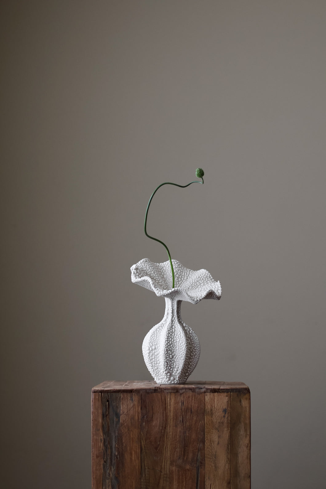 Hand-built white ceramic vase with a heavily textured, dimpled surface and a dramatically ruffled, undulating top.