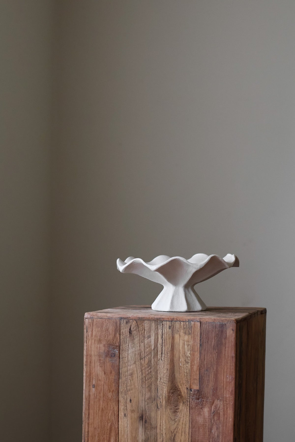 Hand-built white ceramic bowl with a fluted, faceted pedestal base and a dramatically ruffled, undulating rim.