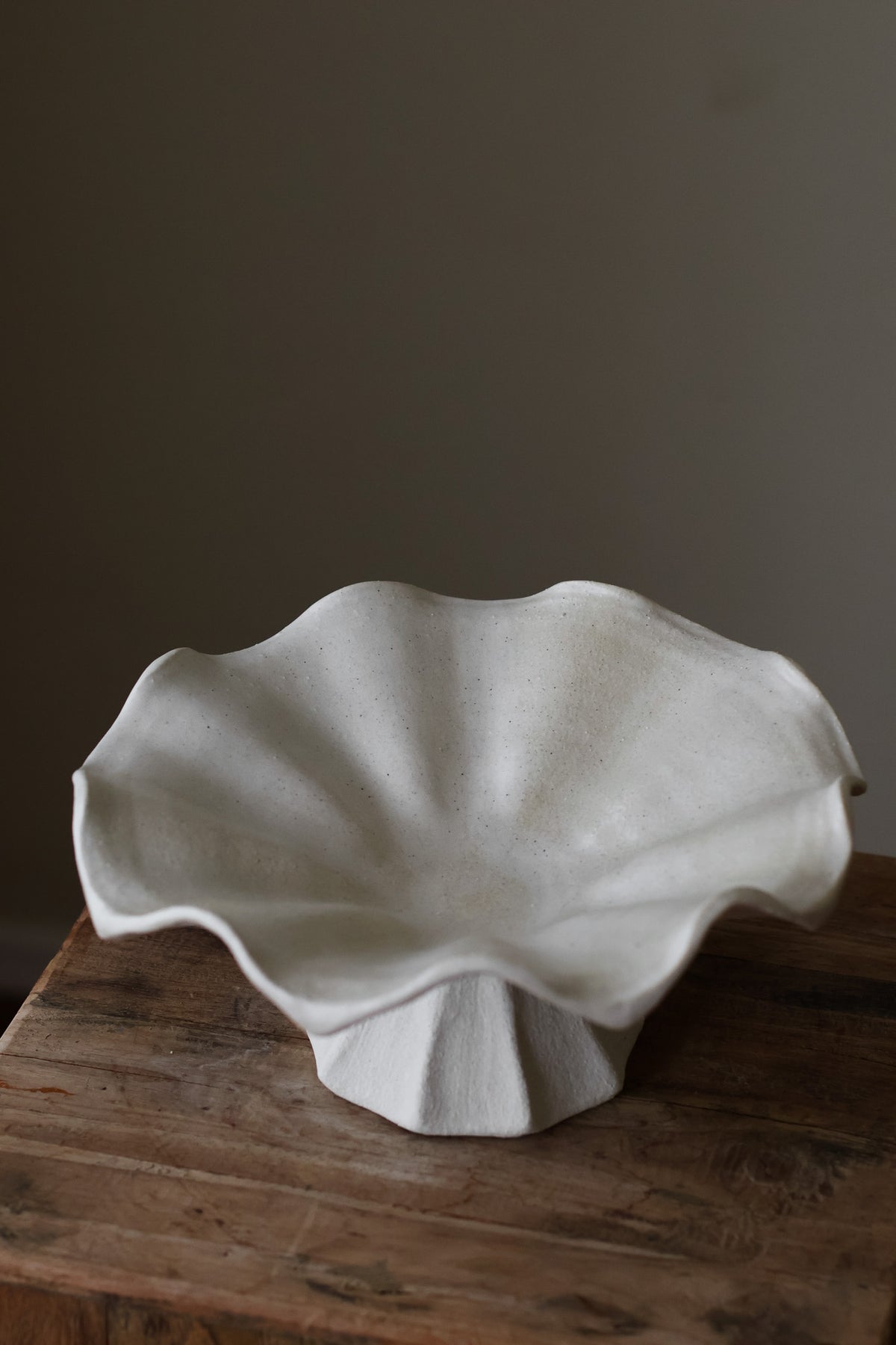 Hand-built white ceramic bowl with a fluted, faceted pedestal base and a dramatically ruffled, undulating rim.