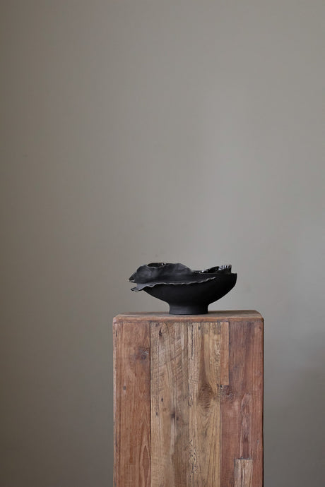 Hand-built dark ceramic bowl with a heavily textured surface, an irregular, sculpted rim, and thin silver lines along the edge. 