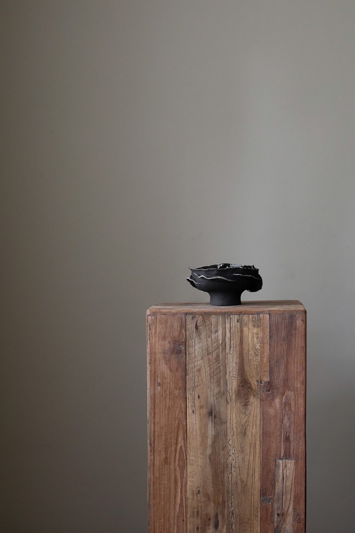 Contemporary sculptural bowl in a deep, dark tone, featuring an organic, irregular rim with silver accents and a rough, textured finish