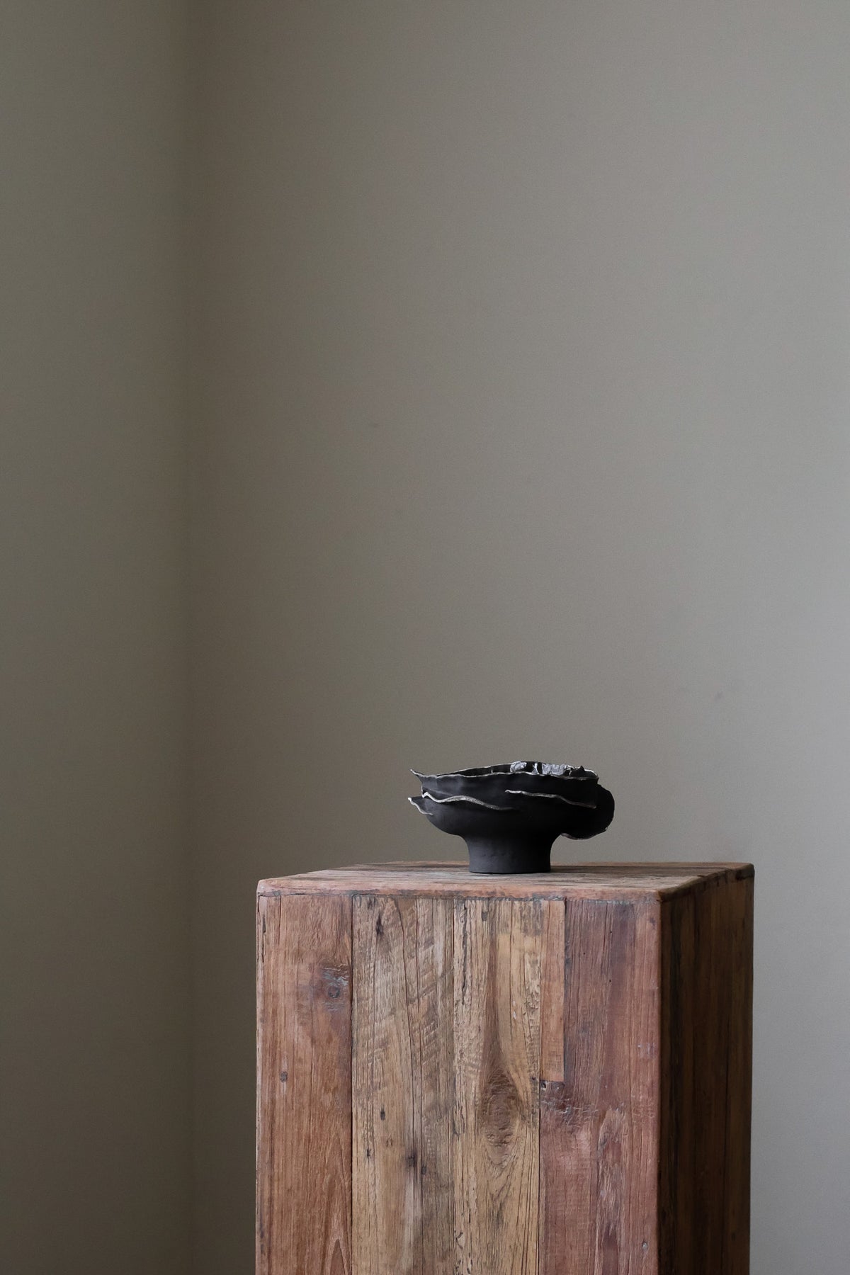Contemporary sculptural bowl in a deep, dark tone, featuring an organic, irregular rim with silver accents and a rough, textured finish