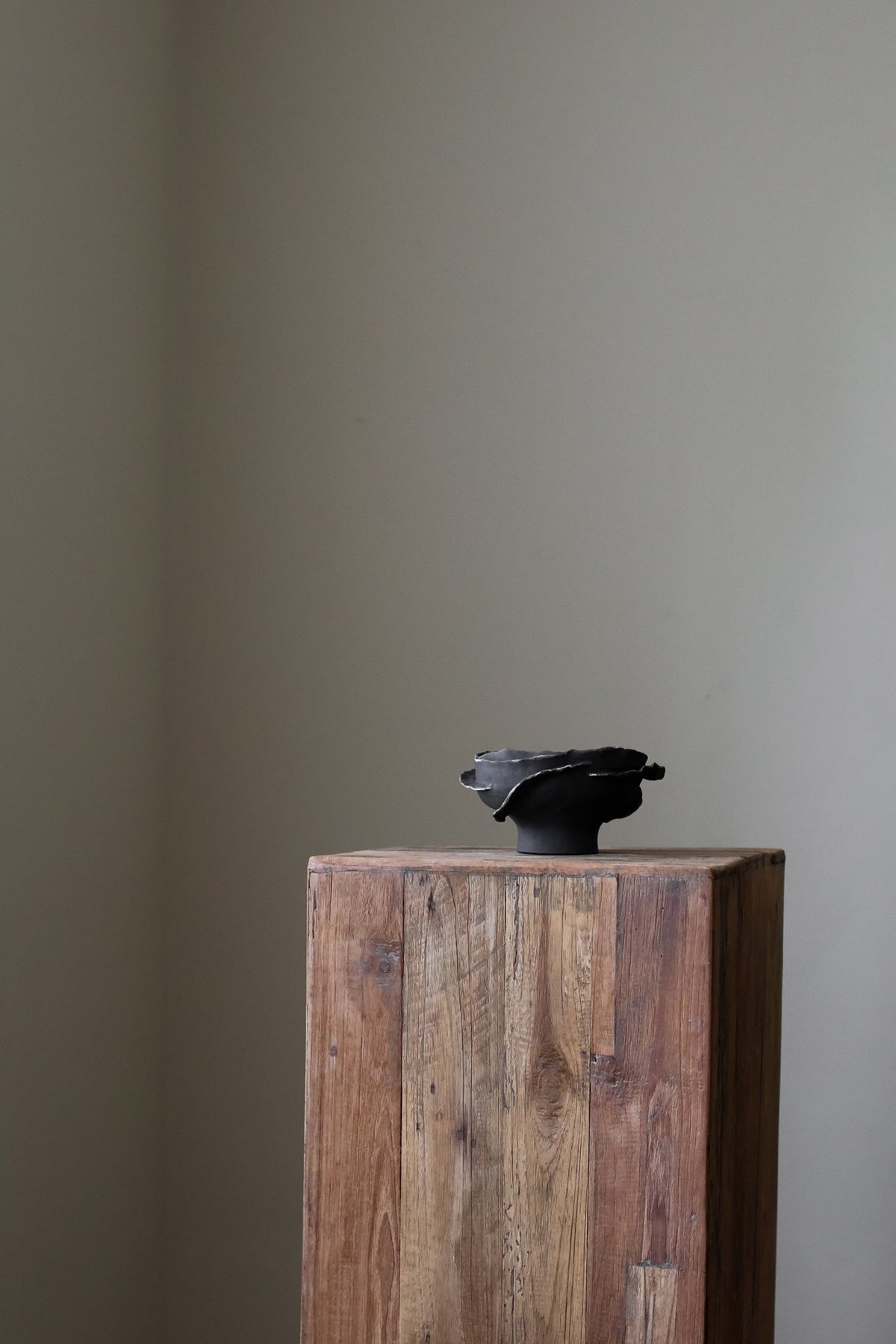 Contemporary sculptural bowl in a deep, dark tone, featuring an organic, irregular rim with silver accents and a rough, textured finish