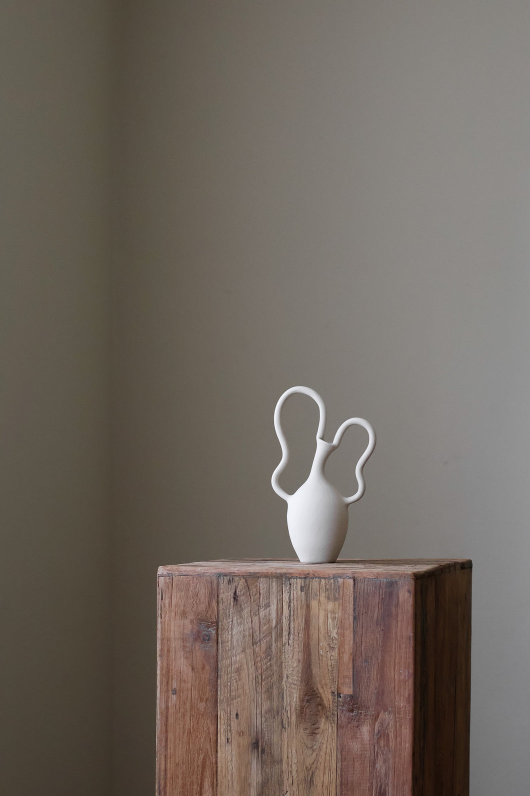 Contemporary sculptural vase in bright white, featuring two unique, flowing handles and a simple, rounded body.