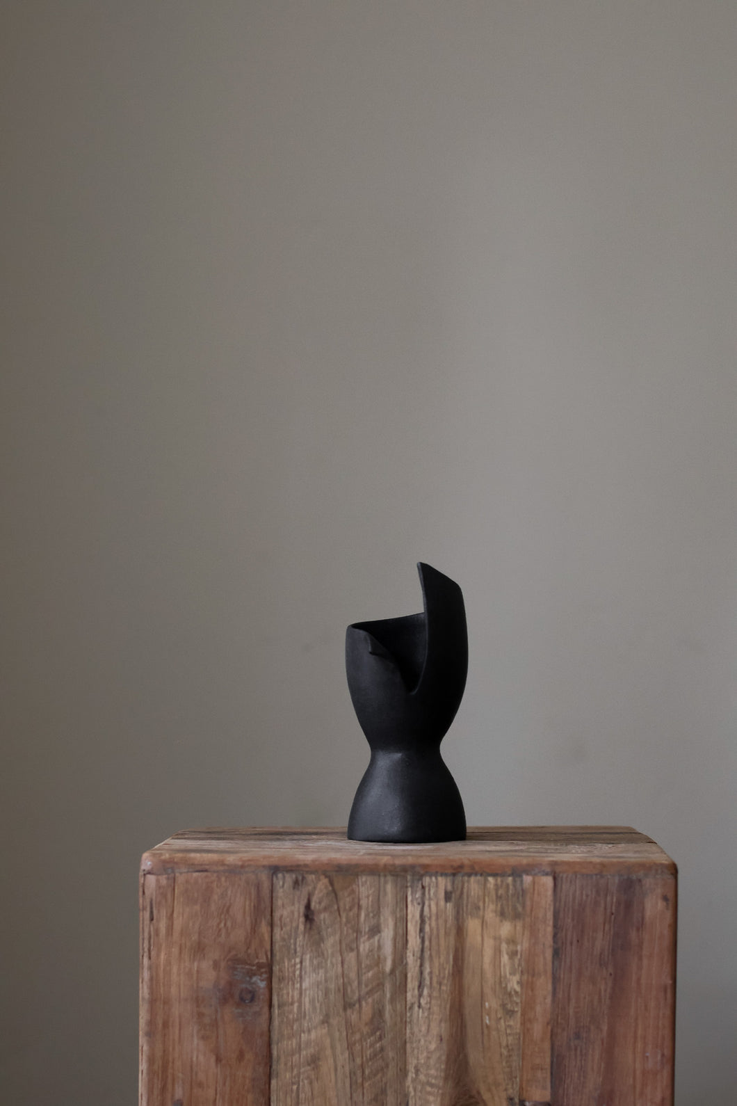 Contemporary sculptural vase in a deep, dark tone, featuring a unique, curved shape and a dynamic, abstract aesthetic.