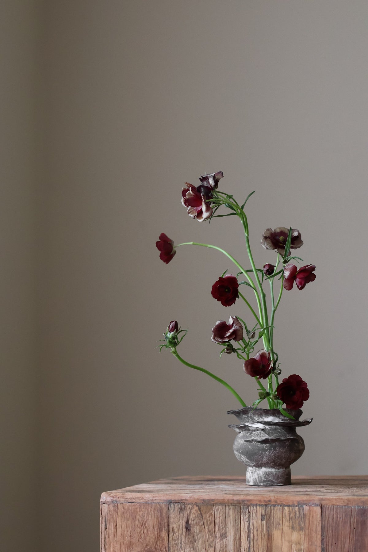 Contemporary sculptural vase in a dark, weathered tone, featuring a unique, layered, and ruffled top design with a rough, organic aesthetic.