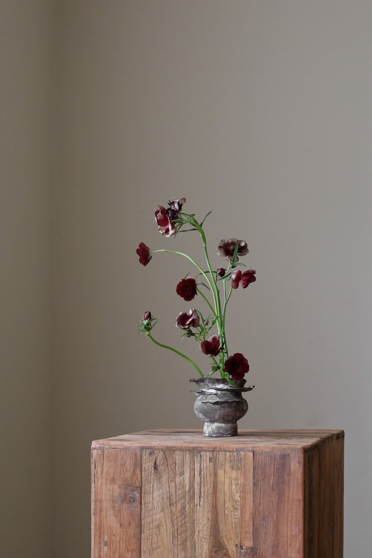 Contemporary sculptural vase in a dark, weathered tone, featuring a unique, layered, and ruffled top design with a rough, organic aesthetic.
