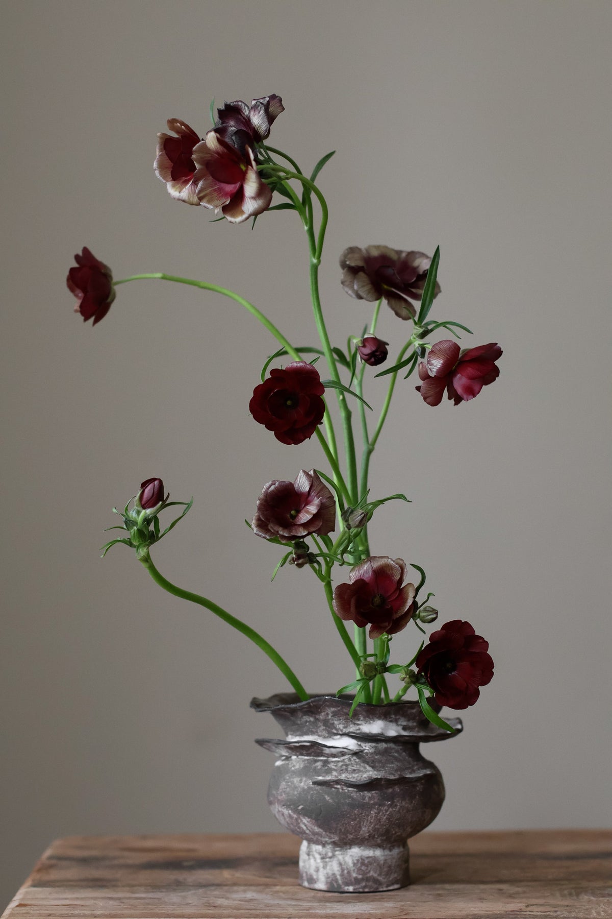 Contemporary sculptural vase in a dark, weathered tone, featuring a unique, layered, and ruffled top design with a rough, organic aesthetic.