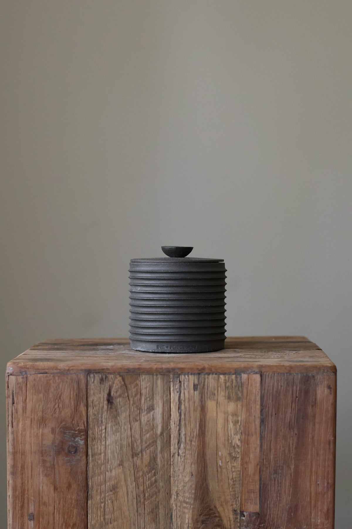 Textured cylindrical container with a removable lid, featuring a matte finish and a modern, minimalist design.