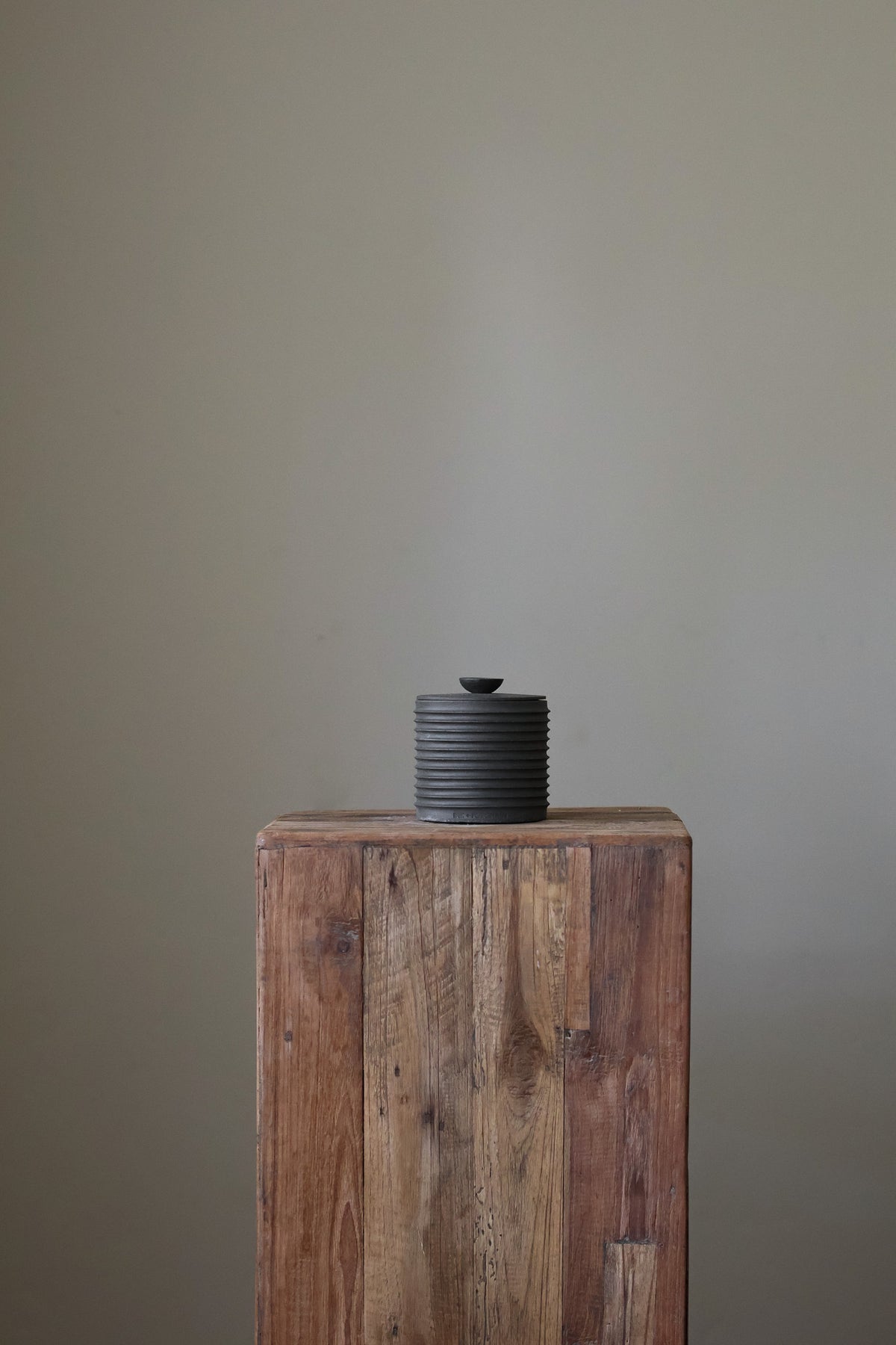 Textured cylindrical container with a removable lid, featuring a matte finish and a modern, minimalist design.