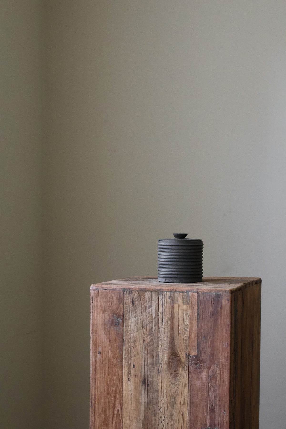 Textured cylindrical container with a removable lid, featuring a matte finish and a modern, minimalist design.