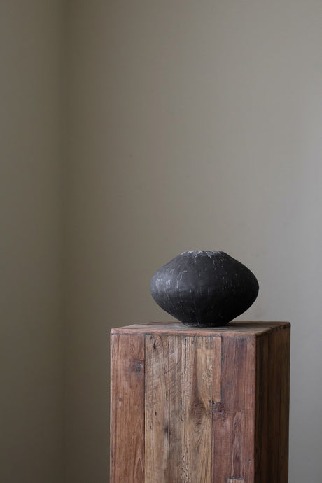 Black ceramic vase by Giselle Hicks, featuring a heavily textured surface and a rounded, organic form. 