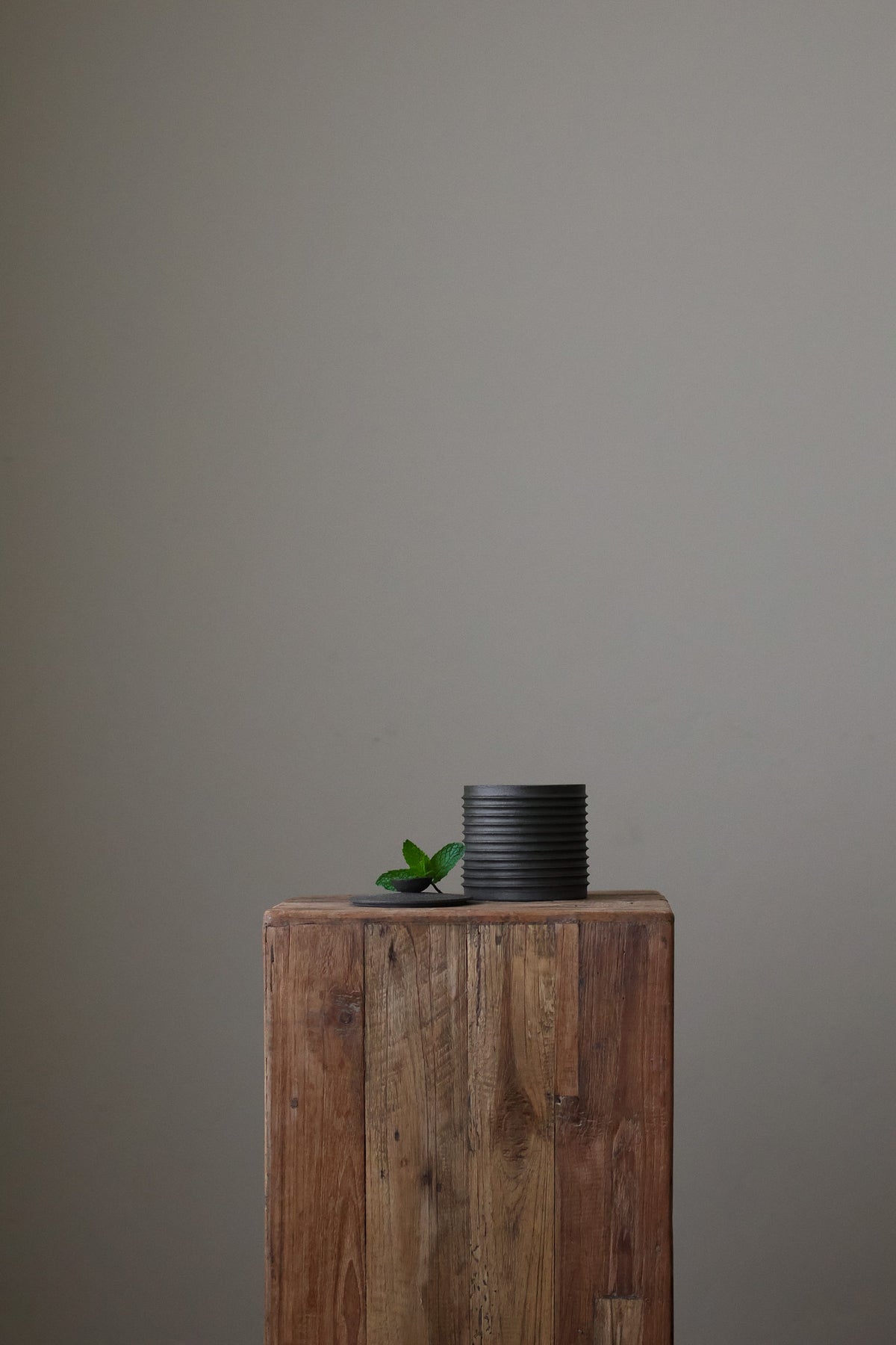 Textured cylindrical container with a removable lid, featuring a matte finish and a modern, minimalist design.
