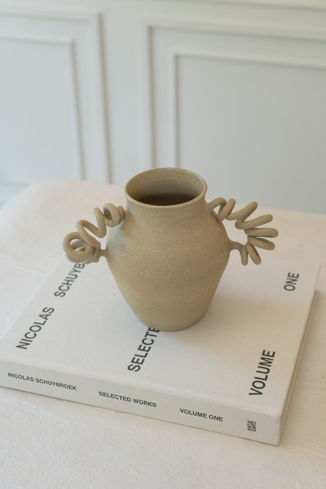 The Big Boinggg Vase in Dune - tan available exclusively on INK + PORCELAIN. The Big Boinggg Vase is a whimsical object of art with spring-inspired handles that bring movement to any space. Handmade by Kuu Pottery.
