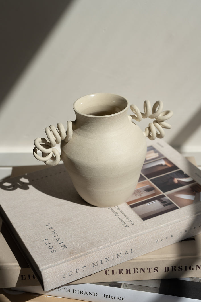 The Big Boinggg Vase in Cream - Beige available exclusively on INK + PORCELAIN. The Big Boinggg Vase is a whimsical object of art with spring-inspired handles that bring movement to any space. Handmade by Kuu Pottery.