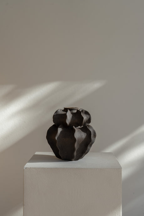  Featuring a raw textured black exterior and a clear glazed interior. Hand-built with visible artistic gestures, the vase captures the beauty of imperfections and adds a dynamic, organic touch to any interior. Its fluid, ripple-like design enhances any space with timeless elegance.
