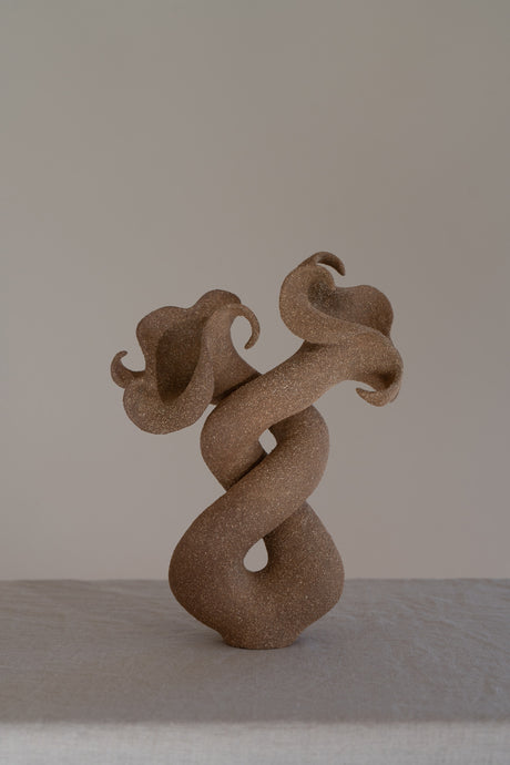 A striking matte brown ceramic vessel with curvaceous and organic shapes, combining soft brutalism with nature-inspired design. 