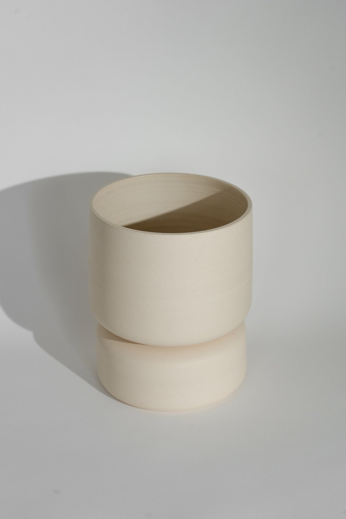 Crafted in cream with a sleek two-piece design, this stylish planter elevates any space. Featuring a removable top for easy water disposal or self-watering, it enhances your home décor while showcasing nature's beauty.