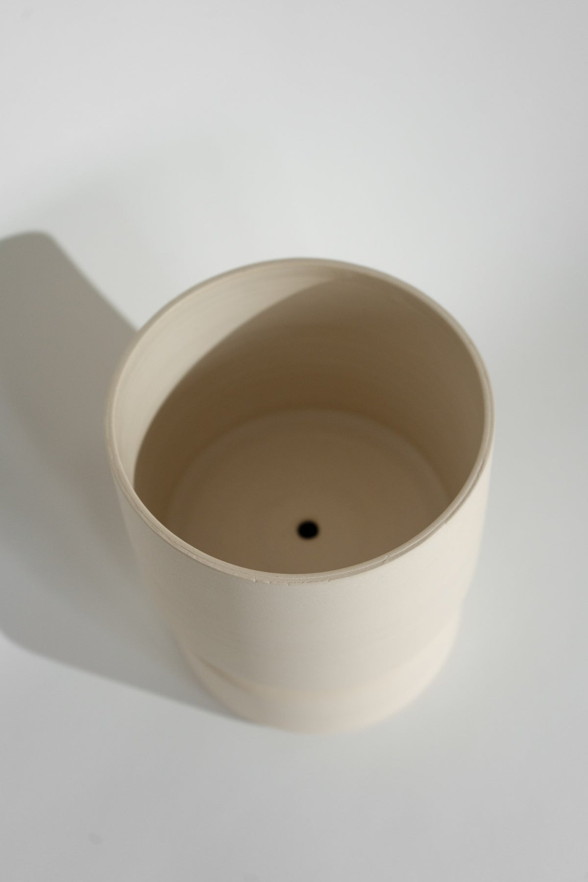 Crafted in cream with a sleek two-piece design, this stylish planter elevates any space. Featuring a removable top for easy water disposal or self-watering, it enhances your home décor while showcasing nature's beauty.