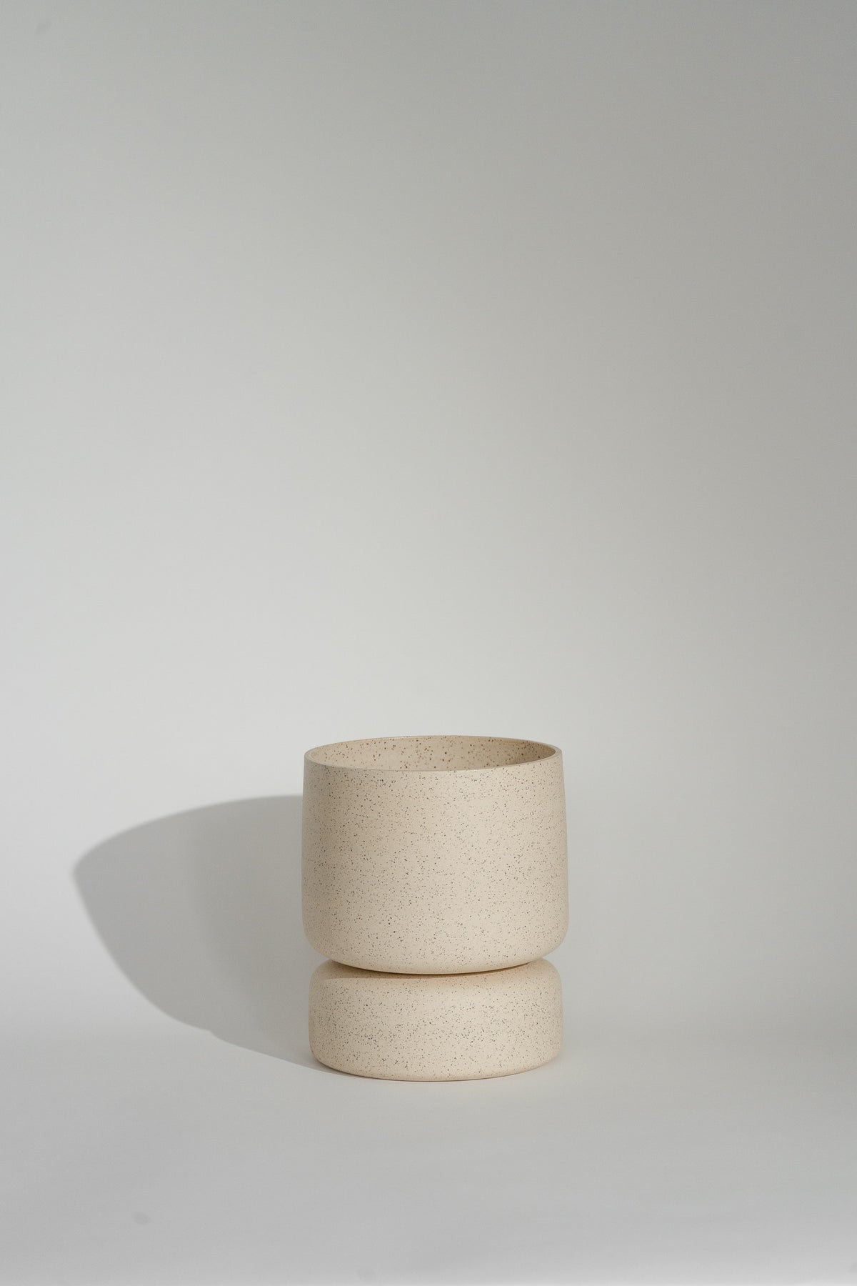 Crafted in cream with a sleek two-piece design, this stylish planter elevates any space. Featuring a removable top for easy water disposal or self-watering, it enhances your home décor while showcasing nature's beauty.