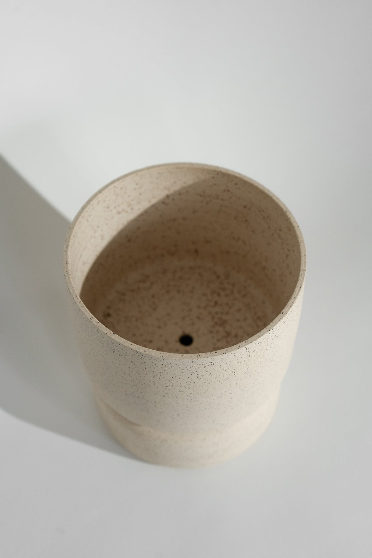 Crafted in cream with a sleek two-piece design, this stylish planter elevates any space. Featuring a removable top for easy water disposal or self-watering, it enhances your home décor while showcasing nature's beauty.