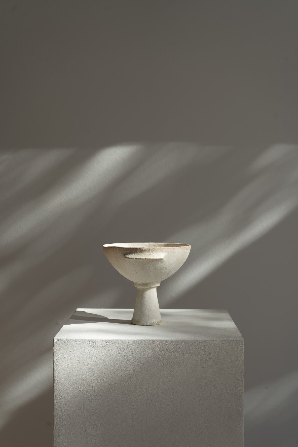 The bowl features a matte cream glaze with a textured surface that evokes ancient Mediterranean artifacts. Its design reflects the fusion of modern and ancient influences, with slight variations that add character to each unique piece.