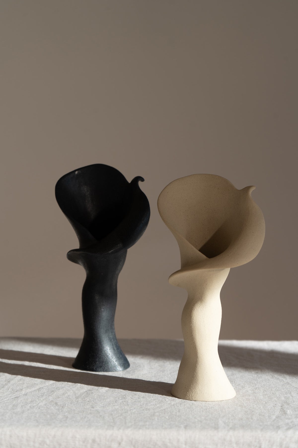 A matte taupe ceramic vase inspired by the Calla Lily, combining bold stoneware with soft floral curves. 