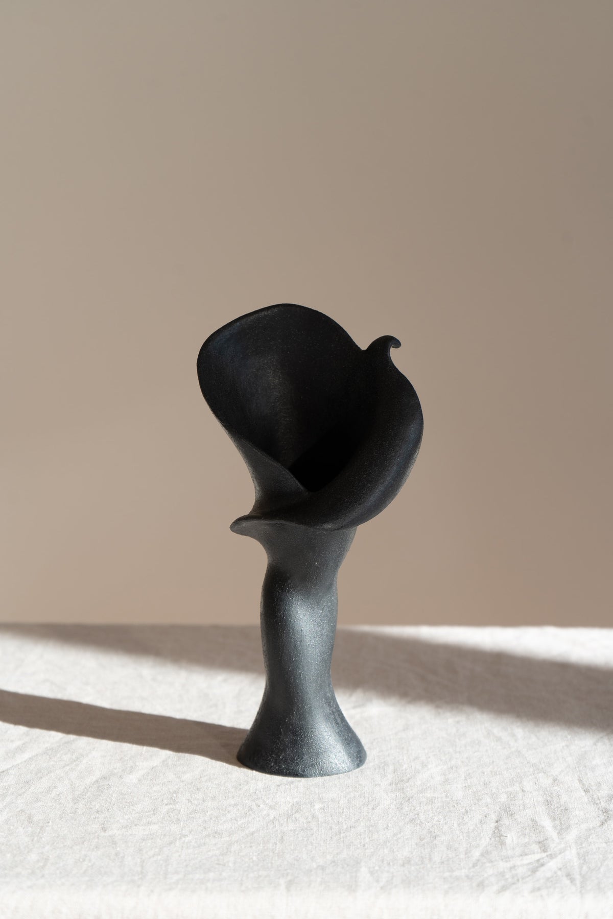  A matte black ceramic vase inspired by the Calla Lily, blending floral curves with bold stoneware. Features a glazed interior, perfect as a striking modern decor piece.