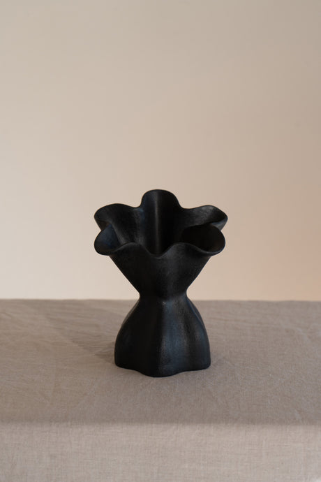 A beautifully crafted matte black ceramic vase with soft, organic shapes and a glazed interior. 