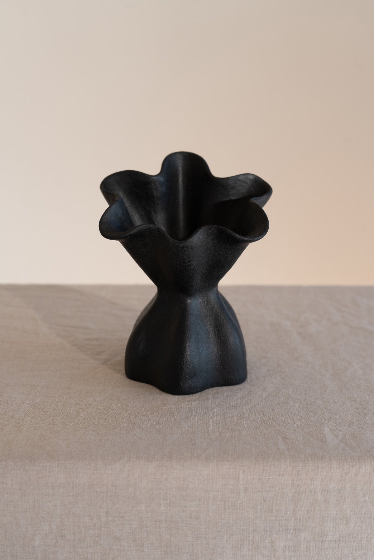 A beautifully crafted matte black ceramic vase with soft, organic shapes and a glazed interior. 